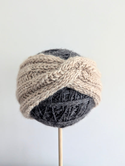 Knitted headband on a mannequin head against a plain background