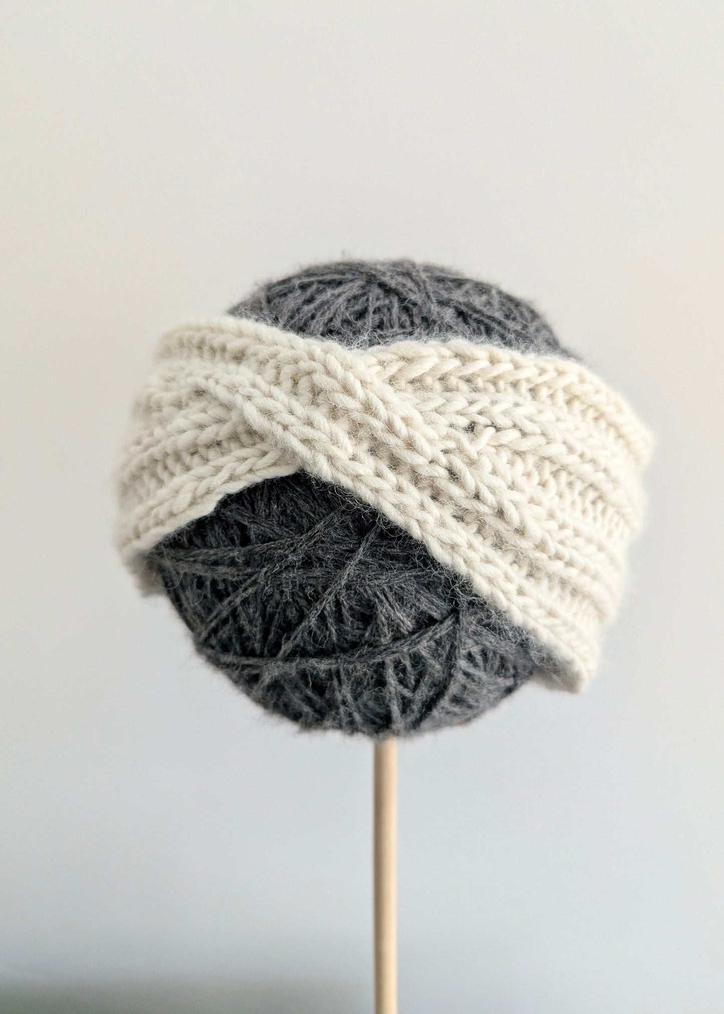 Knitted headband on a ball of gray yarn with a white background
