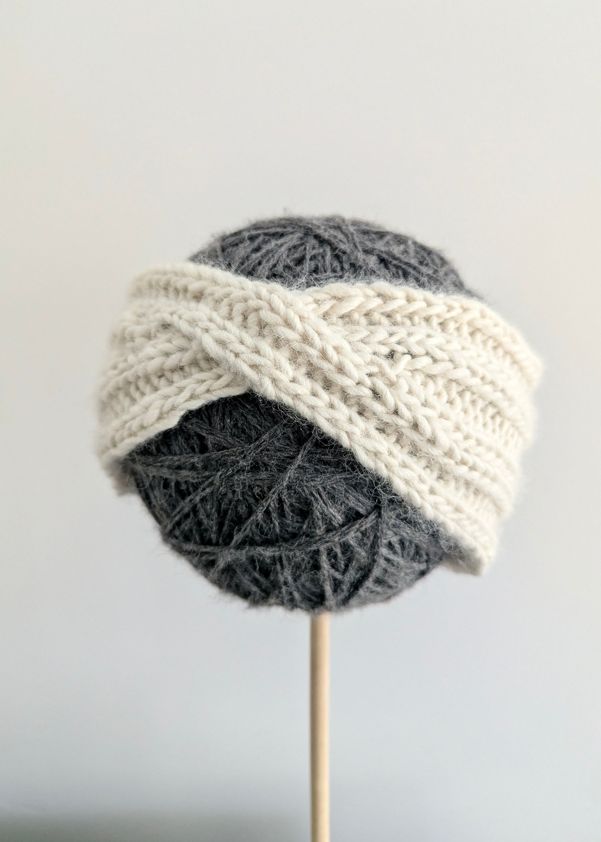 Knitted headband on a ball of gray yarn with a white background