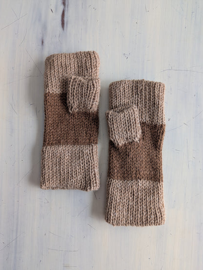 Pair of brown and beige knitted fingerless gloves on a light gray surface