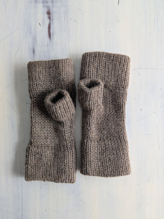 Pair of brown knitted arm warmers on a light gray background
