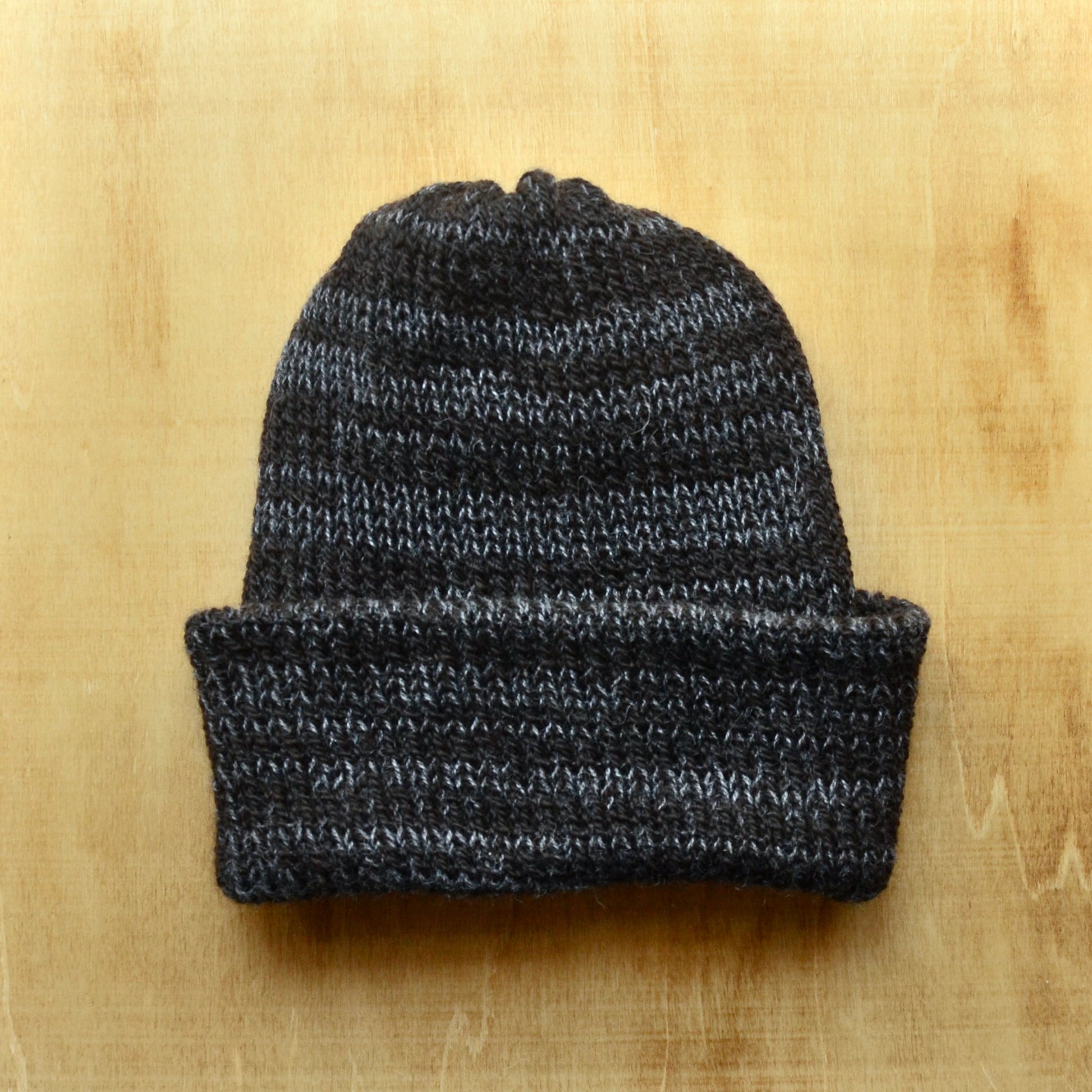 A multicolored knit beanie on a wooden surface.