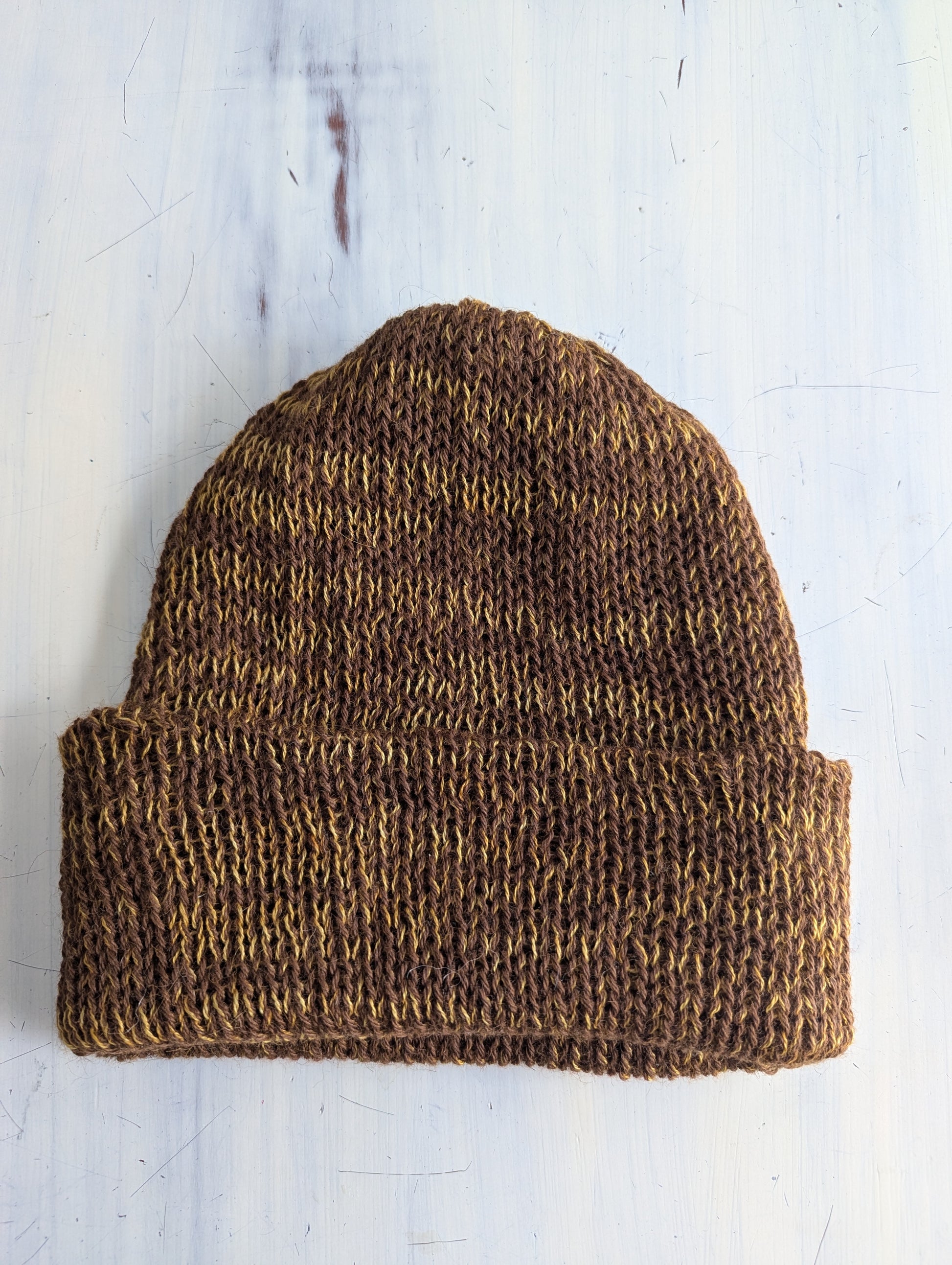 Brown knitted beanie on a light wooden surface