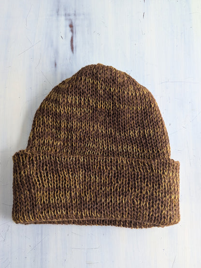 Brown knitted beanie on a light wooden surface