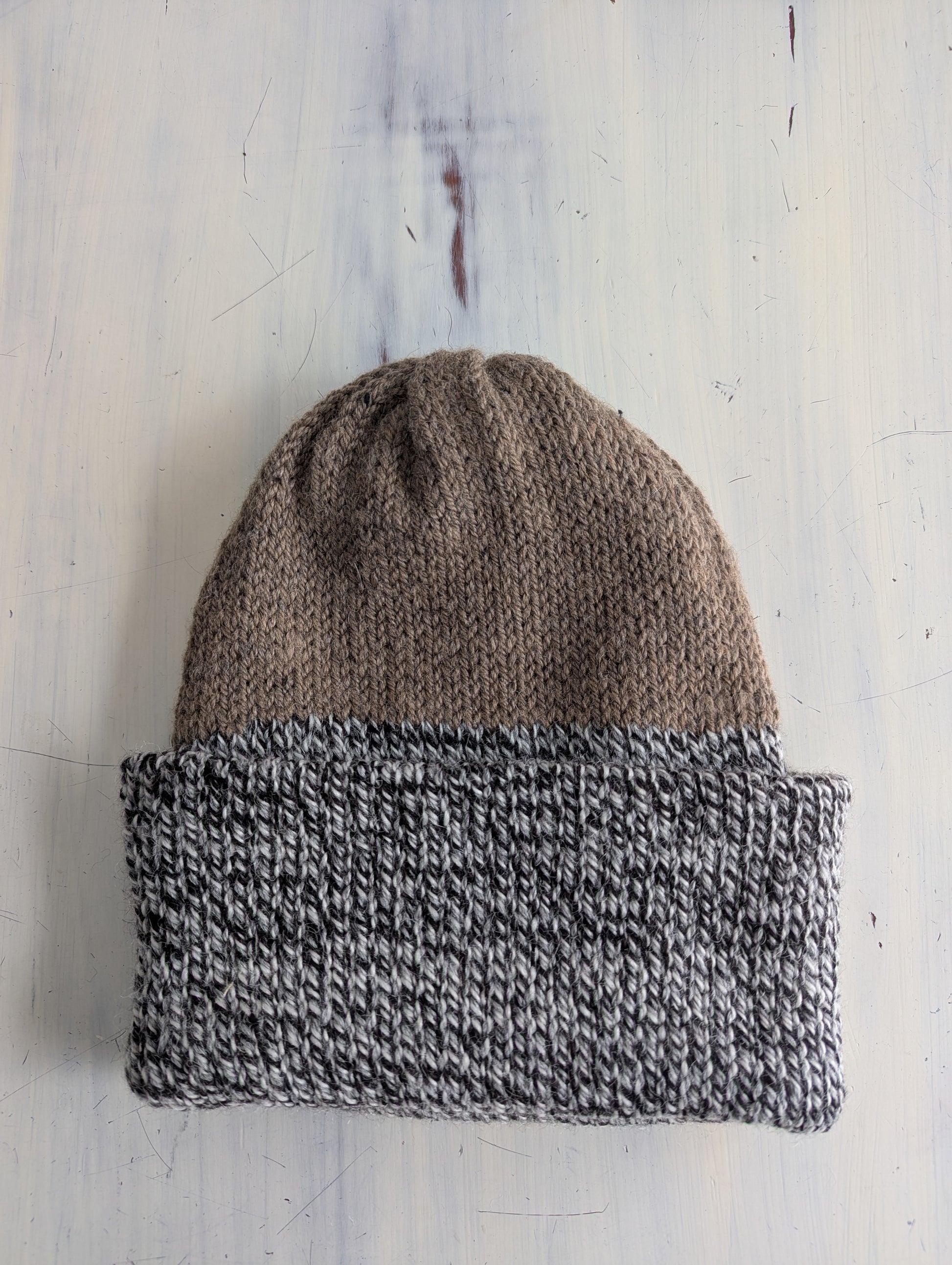 Knitted beanie with two-tone design on a wooden surface