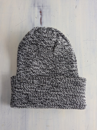 Knitted beanie hat on a light gray textured background
