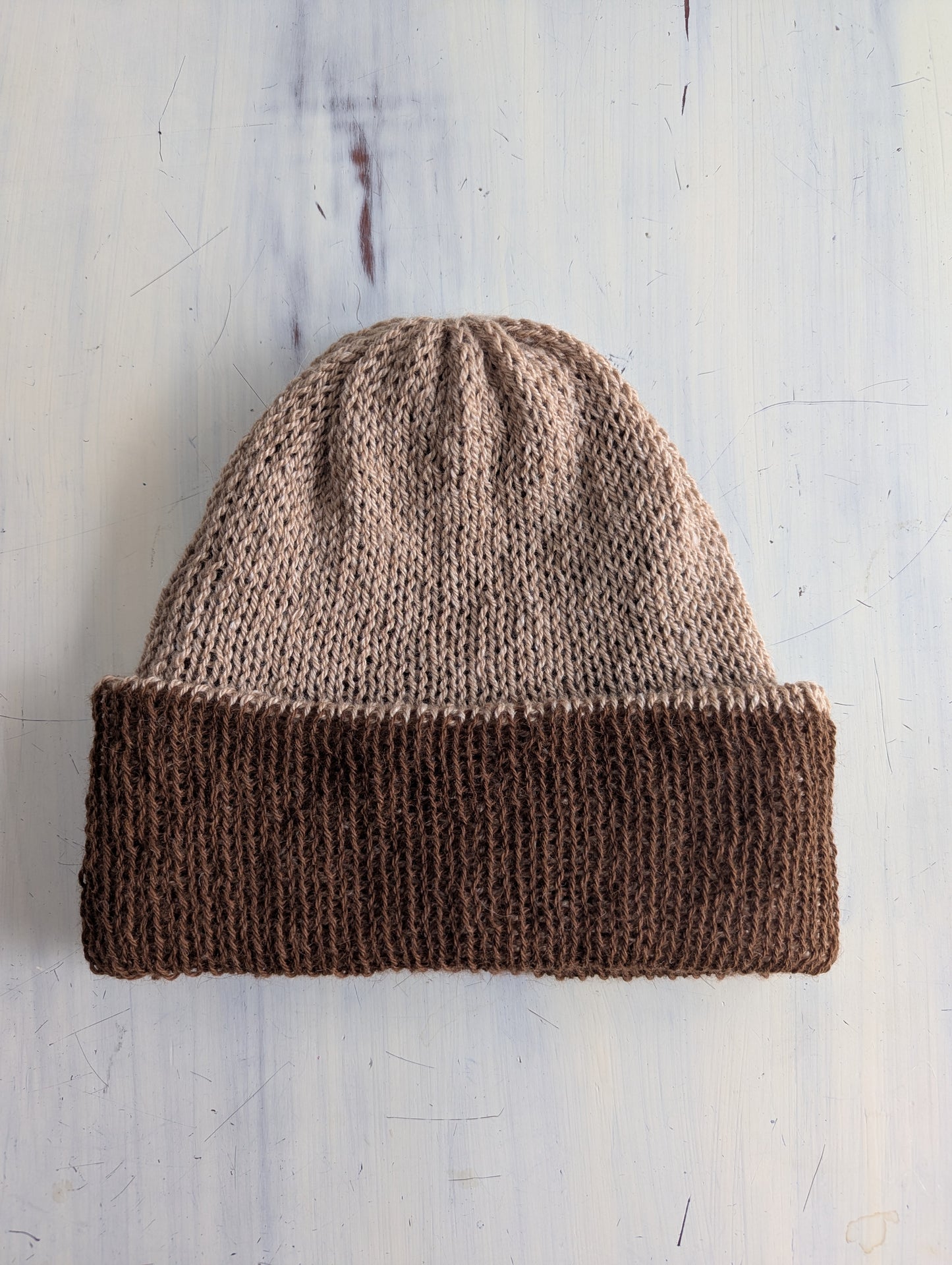 Knitted beanie with two-tone brown design on a light wooden background
