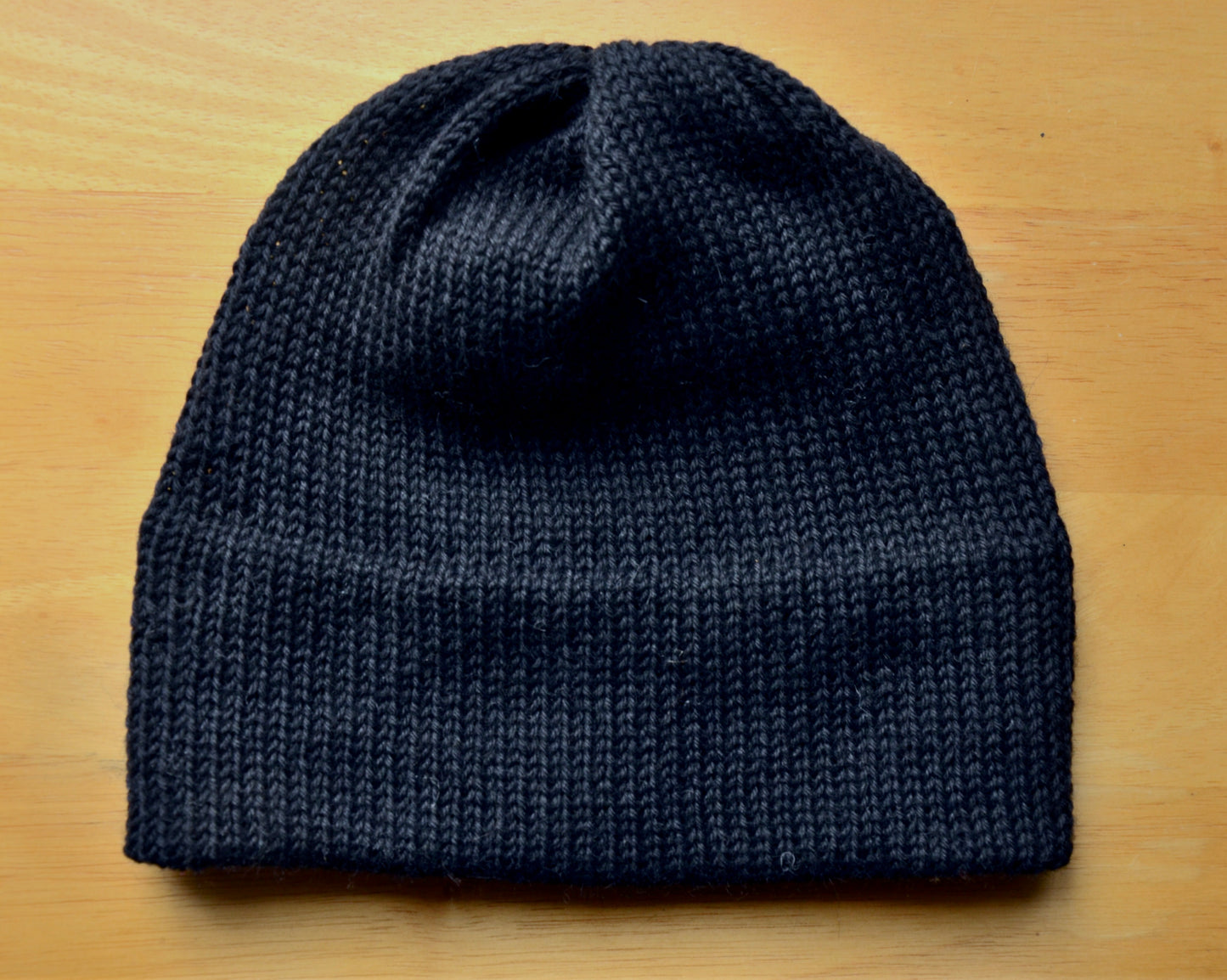 Knit hat from alpaca fibre on wood surface