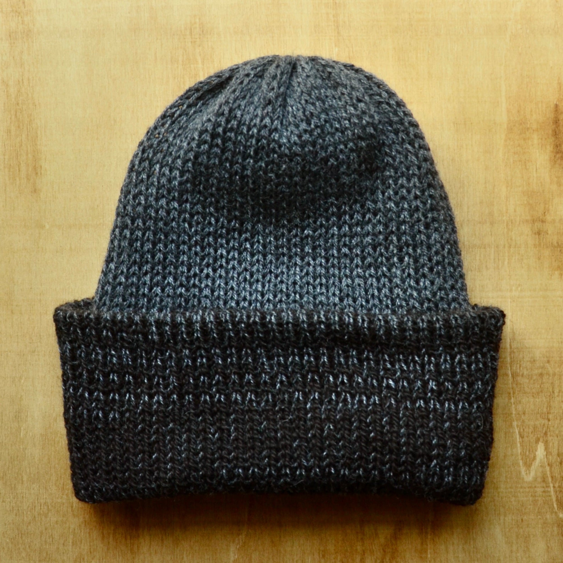 A multicolored beanie with a pom pom on a wooden surface.