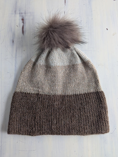 Knitted hat with a pom-pom on a wooden surface