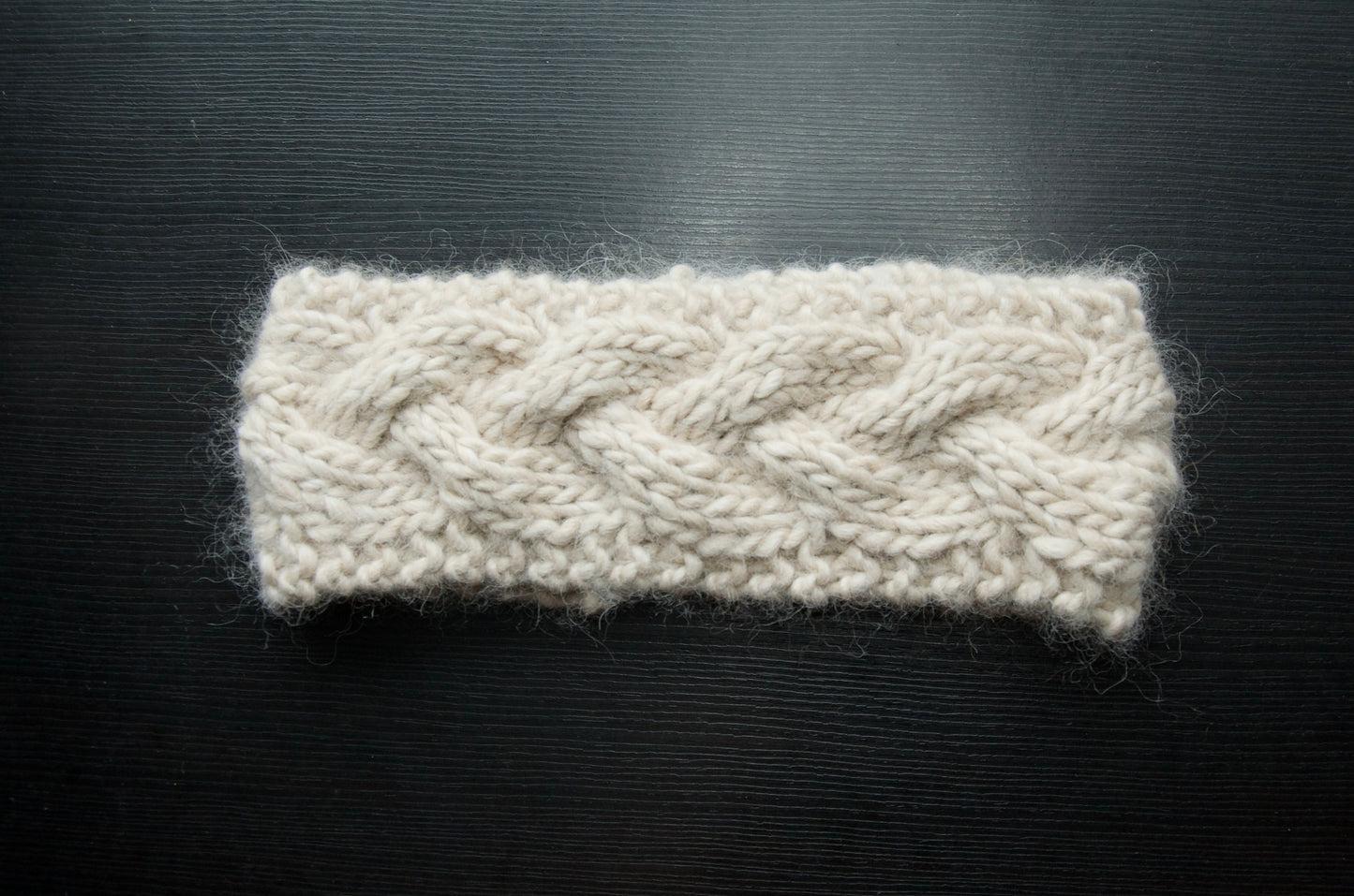 White knit headband with a single braid over a dark background