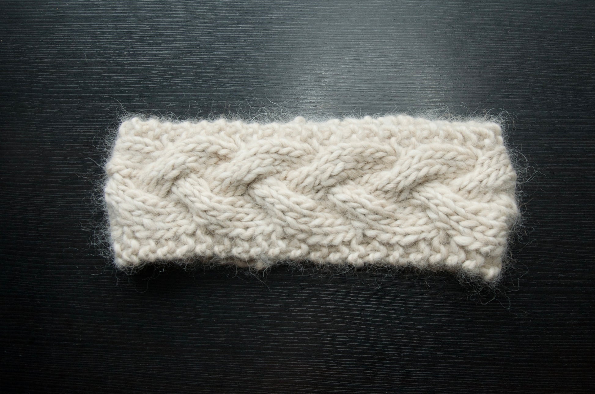 White knit headband with a single braid over a dark background