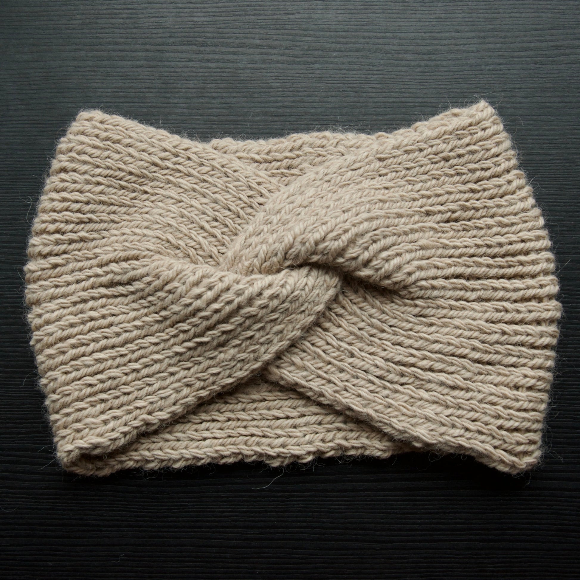 Beige headband flat lay on a dark surface