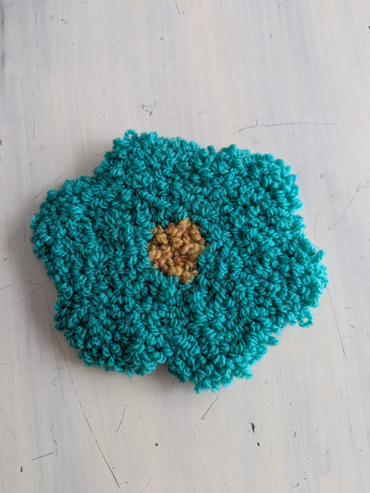 Turquoise textured coaster with a brown center on a light gray surface