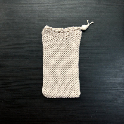 A knit soap saver pouch over a dark surface