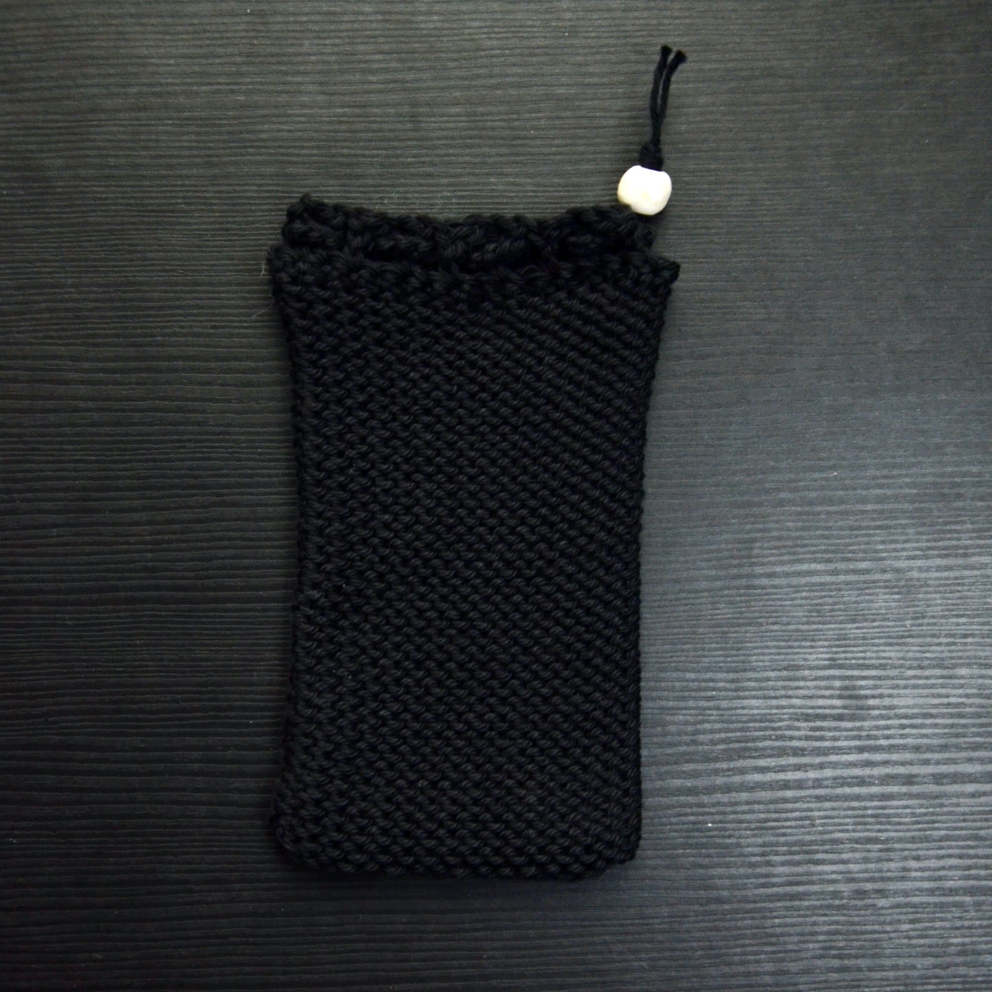 A knit soap saver pouch over a dark surface