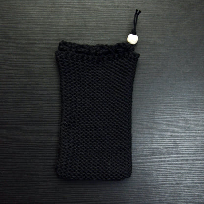 A knit soap saver pouch over a dark surface