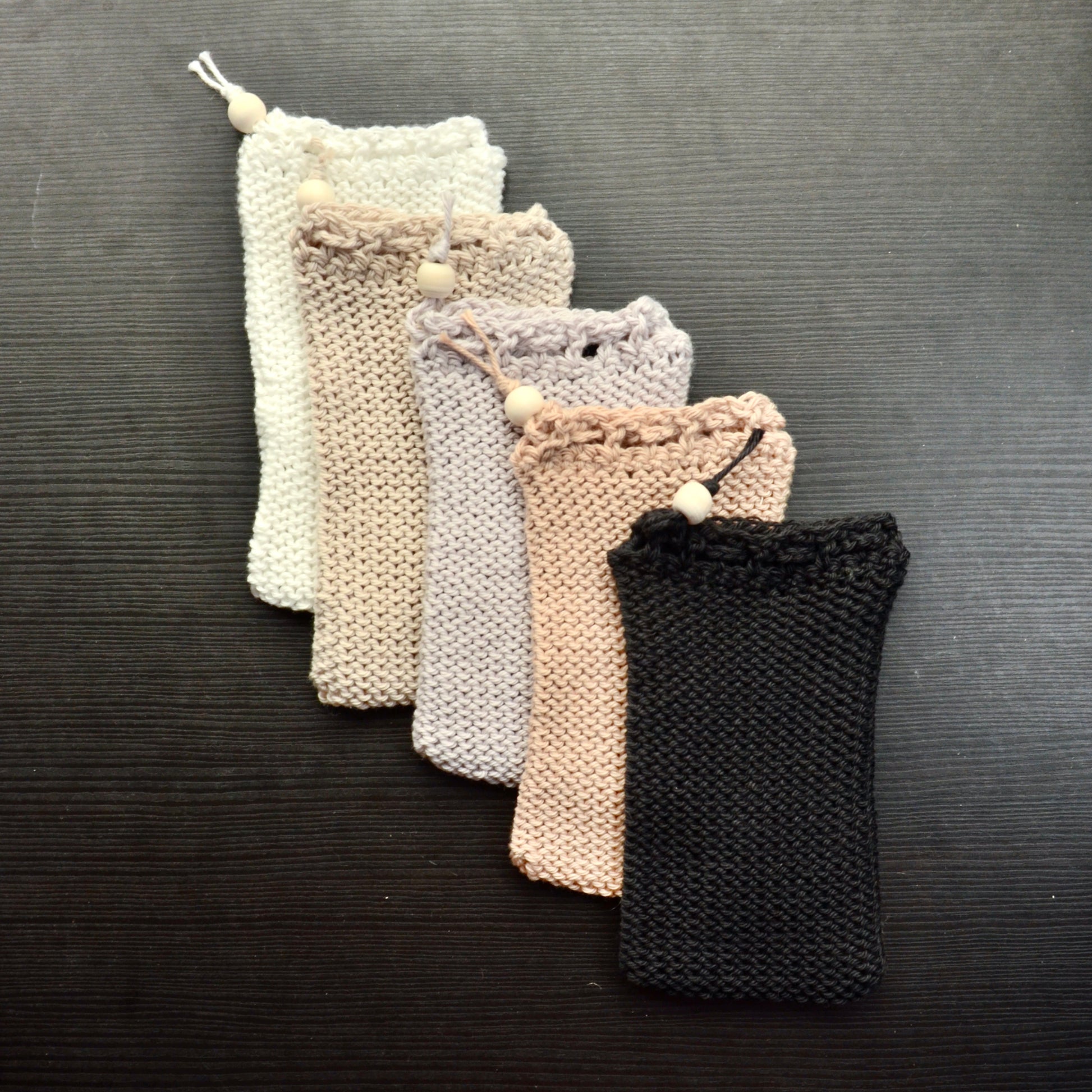 A collection of knit soap saver pouches over a dark surface