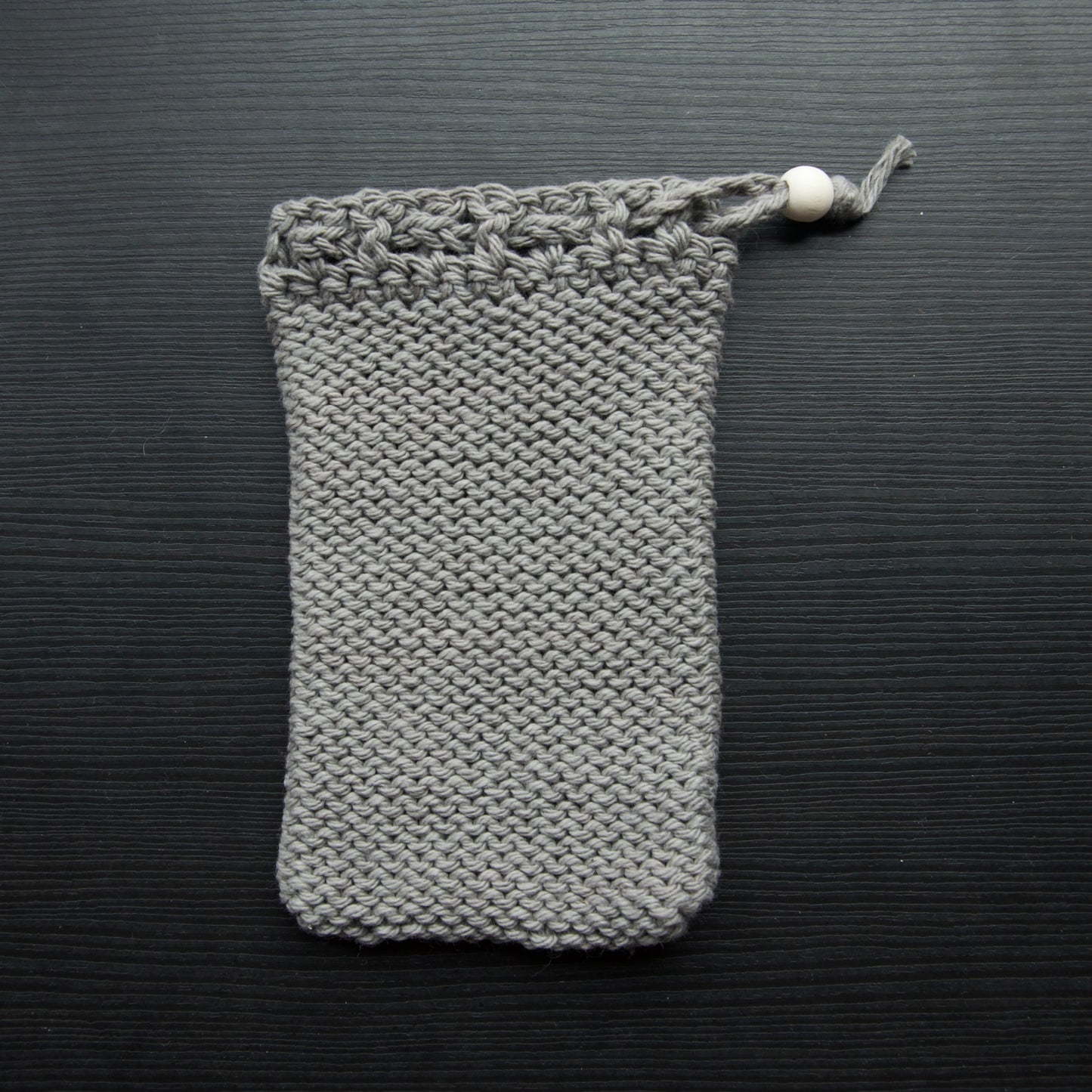 A knit soap saver pouch over a dark surface