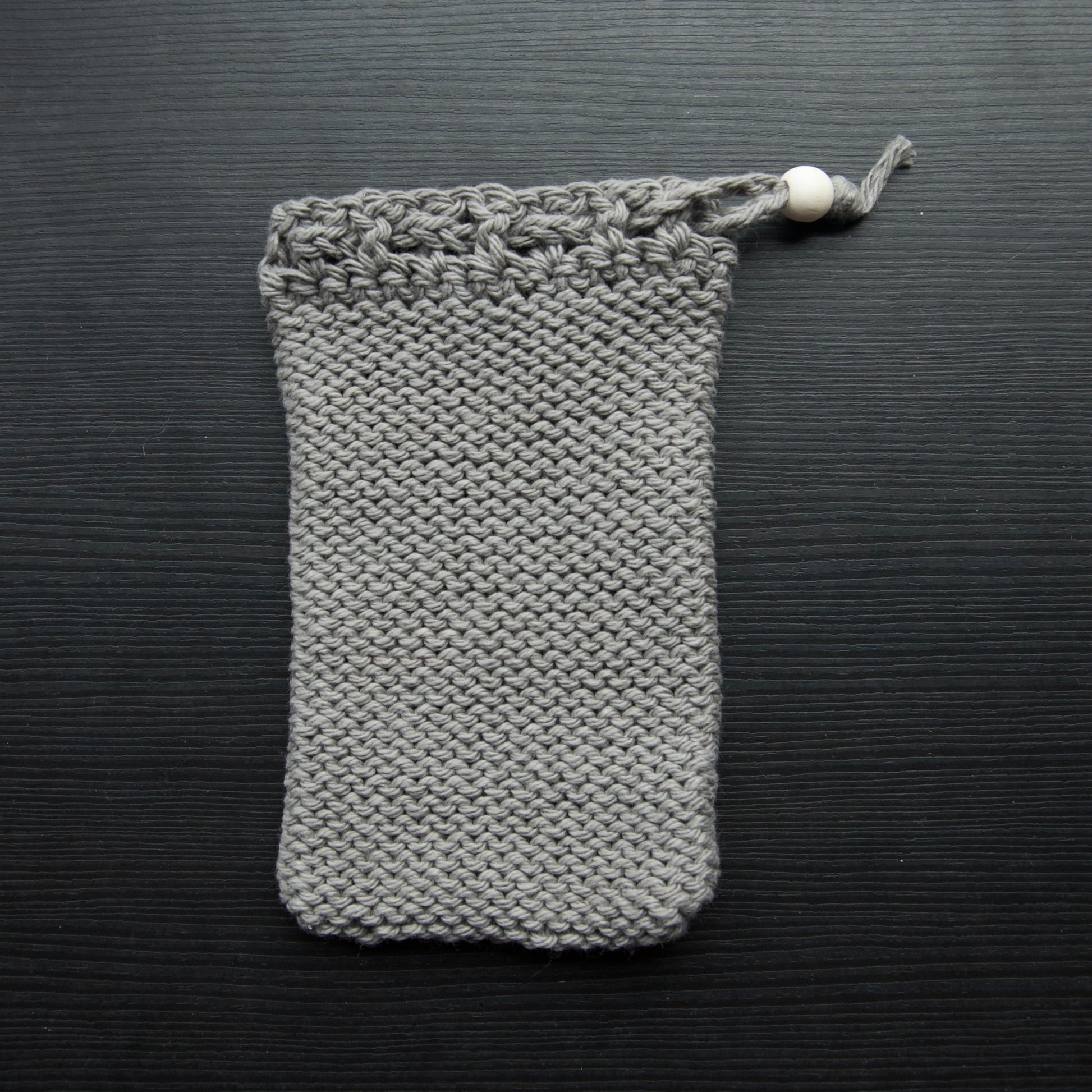 A knit soap saver pouch over a dark surface