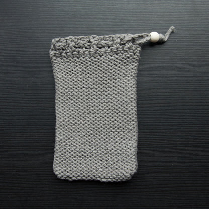 A knit soap saver pouch over a dark surface