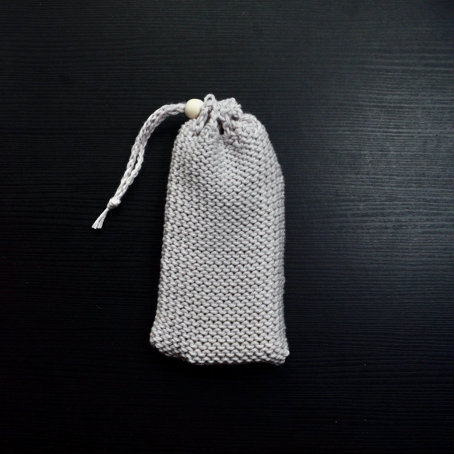 A knit soap saver pouch over a dark surface