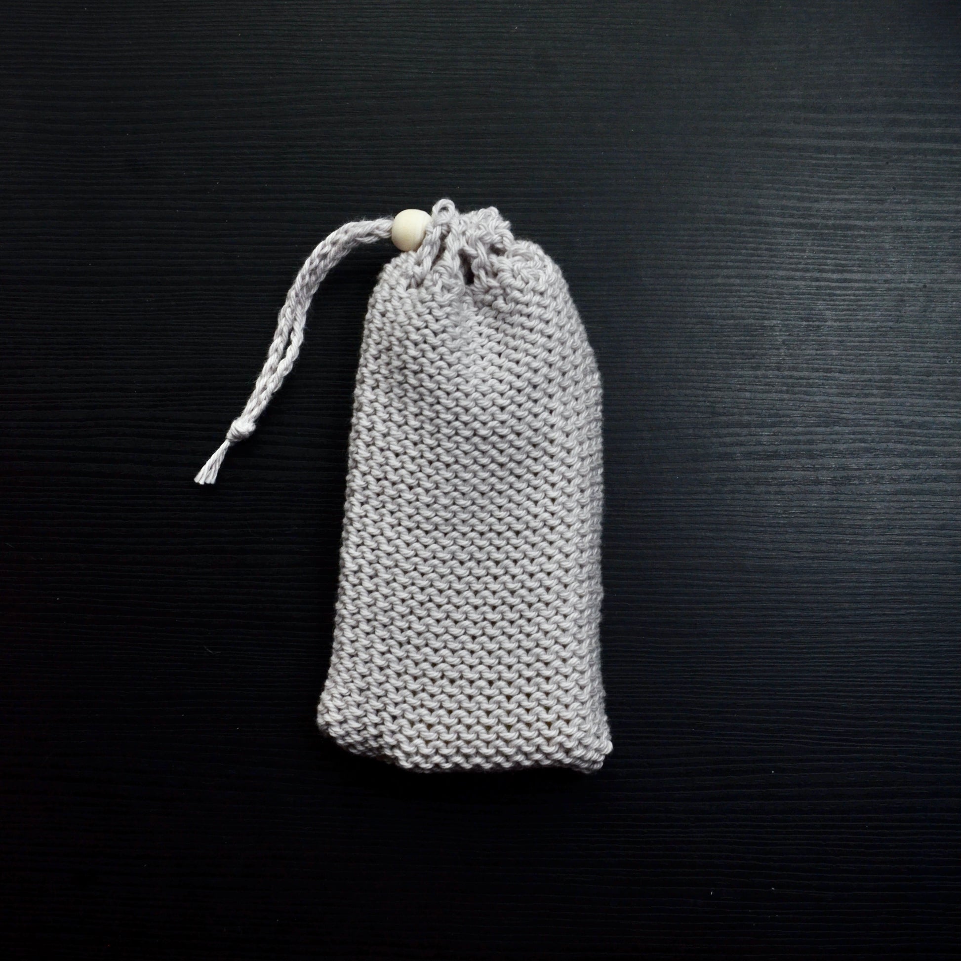 A knit soap saver pouch over a dark surface