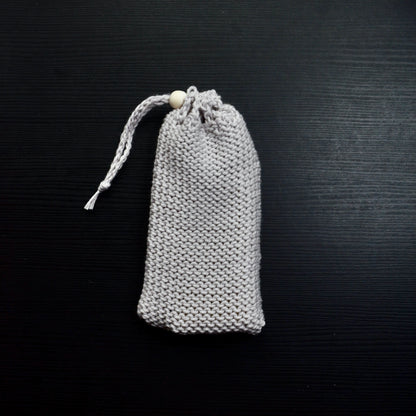 A knit soap saver pouch over a dark surface