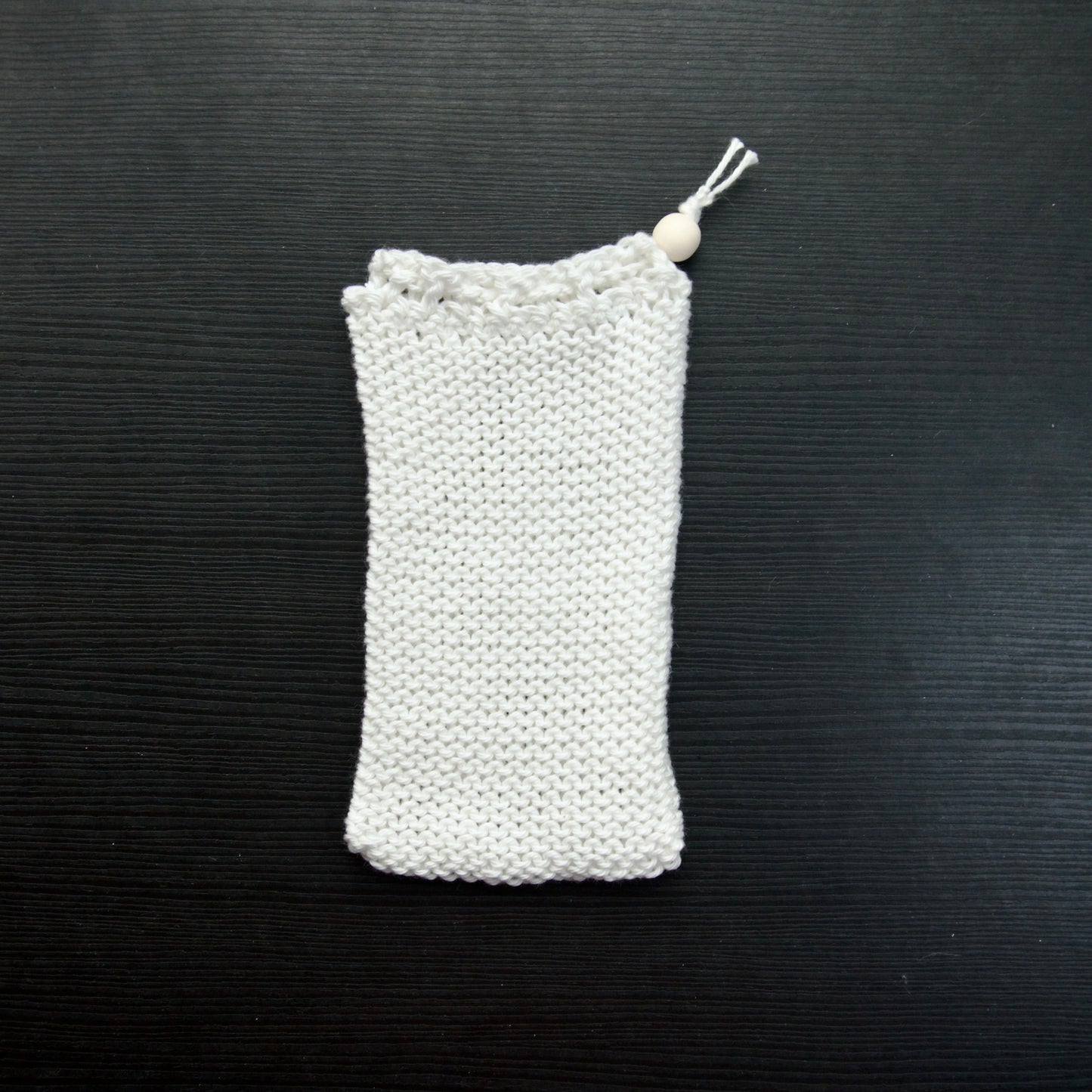 A knit soap saver pouch over a dark surface