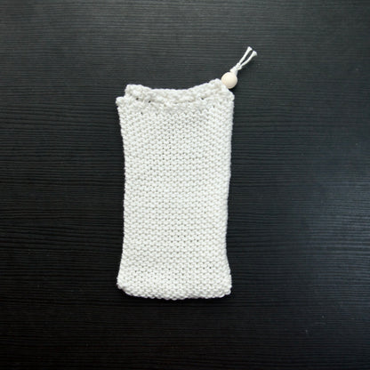 A knit soap saver pouch over a dark surface