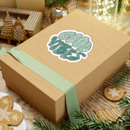 Wooden gift box with 'Good Vibes' sticker, green ribbon, and Christmas-themed cookies.